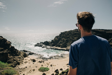 Wall Mural - Young man with sunglasses backwards at Blow Hole Plus Creeck in Oahu landscape