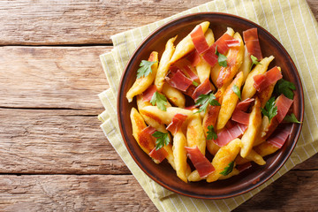 Recipe for German potato noodles called Schupfnudeln, served with bacon and parsley close-up on a plate. Horizontal top view