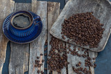 Fototapeta Mapy - on a wooden table, coffee beans and a cup of coffee in a blue cup