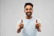 © Syda Productions - gesture and people concept - happy smiling young indian man in t-shirt showing thumbs up