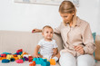 © LIGHTFIELD STUDIOS - adorable toddler sitting on sofa and playing with colorful cubes and mother