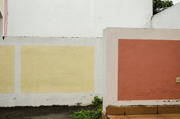 couple of two cement walls painted white and decorated with yellow and red squares, background of a cloudy day