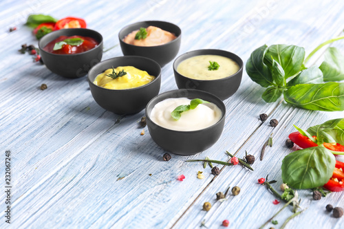 Fotomural Different tasty sauces in bowls with spices on light wooden table