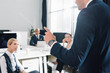 © LIGHTFIELD STUDIOS - cropped shot of young businessman gesturing and talking with colleagues in open space office