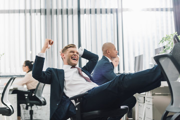 Wall Mural - excited young businessman triumphing while working with colleagues in open space office