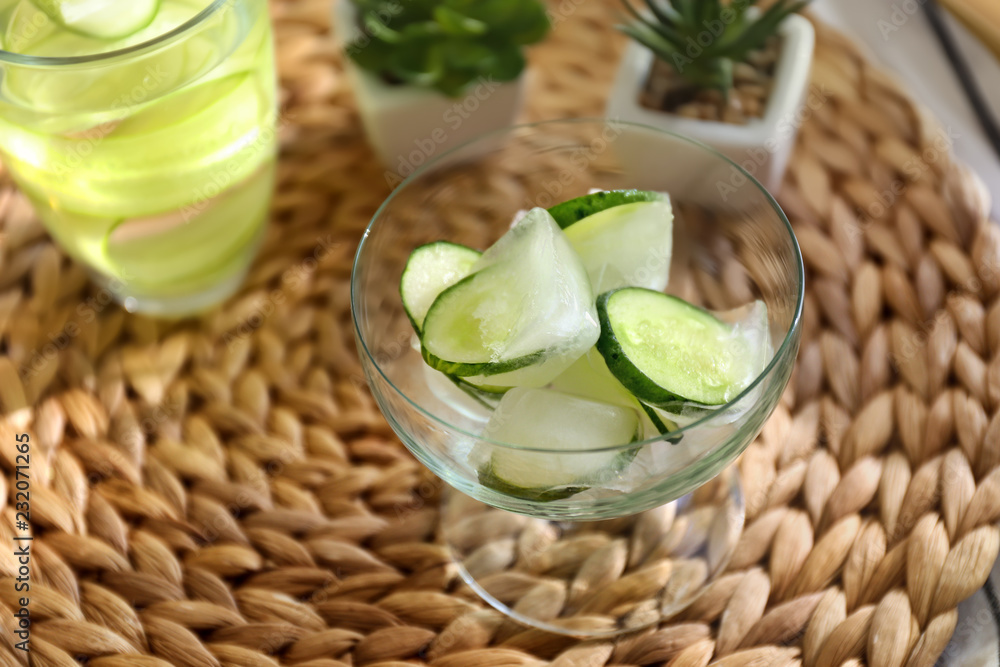 Glass bowl with frozen cucumber slices on wicker mat