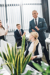 Wall Mural - happy young colleagues applauding to smiling businesswoman in office