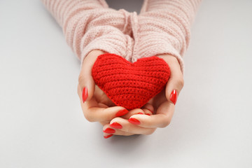 Woman holding knitted heart on white background, closeup