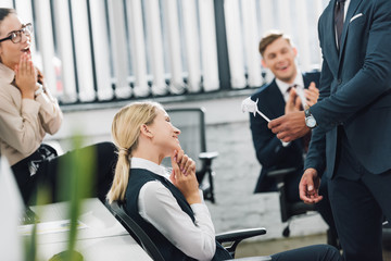 Wall Mural - cropped shot of businessman presenting origami flower to happy businesswoman in office