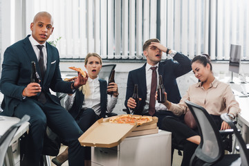 Wall Mural - emotional young business people drinking beer and eating pizza in office