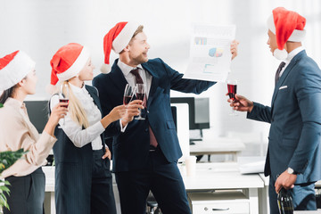 happy young multiracial business people in santa hats celebrating christmas in office