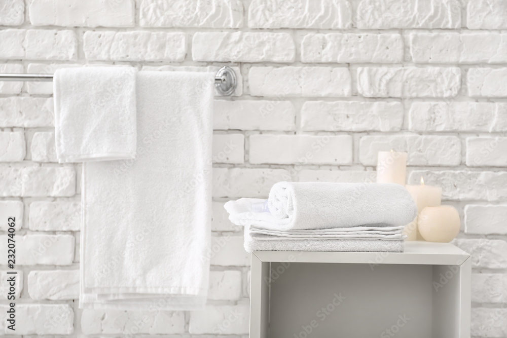 Towels with candles near white brick wall