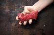 Polędwica wołowa. Kobieta ściska w dłoni kawałek surowego mięsa wołowego.