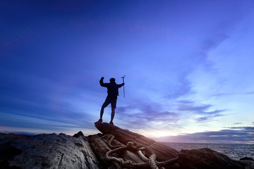 The silhouette of the standing person holding both hands represents the victory on the high mountains and the sun shines through the beautiful surface, success, leadership, achievement and people conc