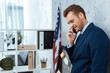 © LIGHTFIELD STUDIOS - cheerful young businessman in suit talking on smartphone in modern office