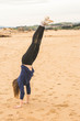 © ADDICTIVE STOCK - girl doing handstand in the sand