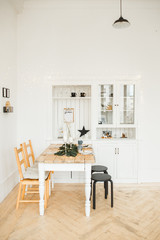 Wall Mural - Christmas table setting. Bright living room with wooden table, decorated with candles, fir branches and Christmas garlands.