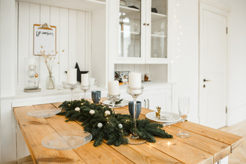 Wall Mural - Christmas table setting. Bright living room with wooden table, decorated with candles, fir branches and Christmas garlands.