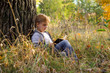 © irina_g - a boy reading a book at sunset under a big tree