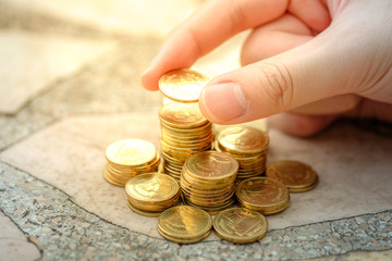 Hand putting coin to stack of coins. Business and Finance, Saving money for future or retirement, investment, financial growth, interest rate increase, inflation, sale price and tax rise concept.