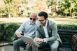 © bnenin - Two business men using laptop outdoors.