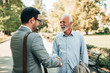© bnenin - Portrait of a senior and young men handshaking in the park.