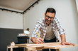 © bnenin - Handsome young craftsman using pencil for marking wood.