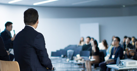 Wall Mural - Panel Speaker on Stage Presenting Vision and Ideas. Conference Lecture Hall. Blurred De-focused Unidentifiable Presenter and Audience. People Attendees. Business Technology Event. Debate Discussion.