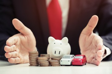 Business man in suit open hand prop up hug model of toy car on over a lot money of stacked coin insurance loan and buying car finance concept. buy and installment down payment a car. Piggy Bank saving