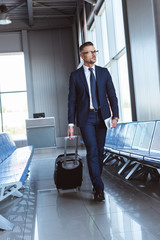 Wall Mural - handsome businessman in glasses walking along departure lounge in airport