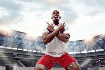 Wall Mural - The football african player in motion on the field of stadium at day. The professional football, soccer player and human emotions concept. The win, winner, victory concept