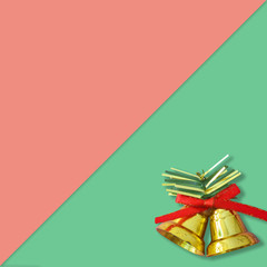 Two golden christmas bells with a red ribbon bow on red and green background, New year greeting card.