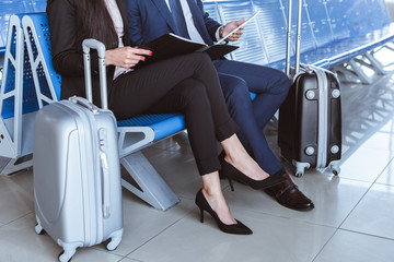 Wall Mural - close up of businessman using digital tablet while businesswoman holding black folder at departure lounge in airport