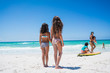 © Schultz-West Images - Two girls walking near family on the beach