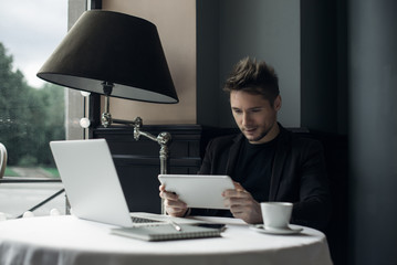 Young man drawing template for the web site associated with digital marketing, current trends and tendencies of UX / UI design. Businessman who rules his company remotely, like a freelancer