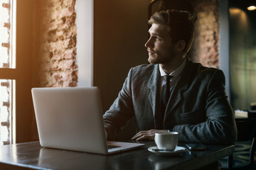 Young handsome man working in the office of mobile network company, adapting tariff plans to users need. Consultant providing service online with notebook. Business running through mobile systems. 