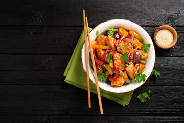 Wall Mural - Stir fry with chicken, vegetables, soy sauce and sesame on black wooden background. 