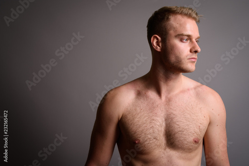 Young Handsome Man With Blond Hair Shirtless Against Gray Backgr