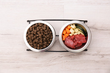 Wall Mural - Bowls with dry and natural dog food on light background, top view