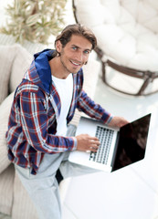 Wall Mural - young man working on laptop and looking at camera. view from above