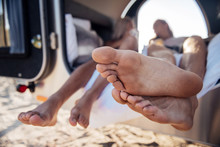 Traveling Couple. Barefooted Man And Woman Lying In Their Mobile Home While Traveling All Around Country