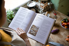 Happy Woman Reading A Cookbook In The Kitchen