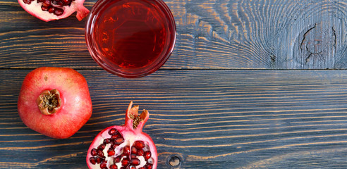 Wall Mural - Ripe pomegranate fruit and a glass of pomegranate juice on wooden table. Healthy eating concept. Banner