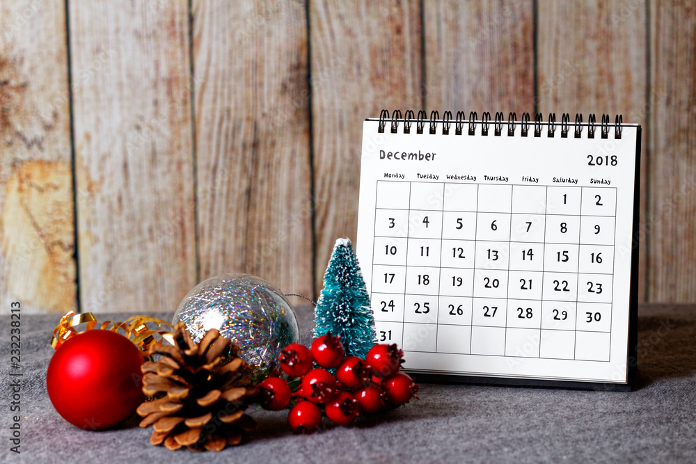 December 2018 calendar and Christmas decoration - baubles, cone and rowanberry on the soft table and wooden wall in the background - obrazy, fototapety, plakaty 