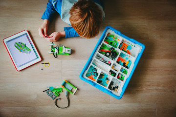 Wall Mural - little boy building robot and programming it with touch pad