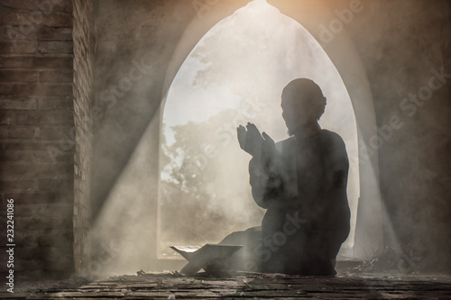 Fotografía Silhouette of muslim male praying in old mosque with lighting and smoke backgrou