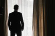 © sonyachny - Stylish groom silhouette in suit posing at window light. Confident and happy portrait of man. Groom getting ready in morning. Wedding photo