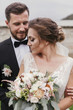 © sonyachny - Gorgeous bride with modern bouquet and stylish groom gently hugging and smiling outdoors. Sensual wedding couple embracing. Romantic moments of newlyweds. Wedding photo
