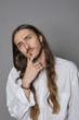 © Anatoliy Karlyuk - Serious thoughtful young long haired hipster guy wearing stylish white shirt, touching beard, having pensive deep in thoughts look, his eyes full of doubt and uncertainty. Human facial expression