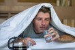 lifestyle home portrait of young exhausted and wasted man waking up suffering headache and hangover after drinking alcohol at night party lying on bed sick